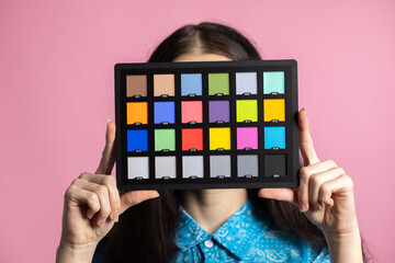 Palette or colorchecker calibration in the hands of a girl. The model holds a color card in its hands for correct color transfer during further color correction.