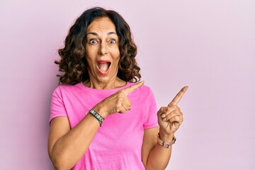 Middle age hispanic woman pointing with fingers to the side celebrating crazy and amazed for...