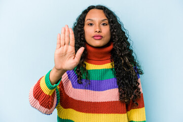 Young hispanic woman isolated on blue background standing with outstretched hand showing stop sign,...