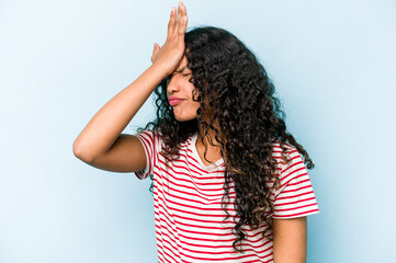 Young hispanic woman isolated on blue background forgetting something, slapping forehead with palm and closing eyes.