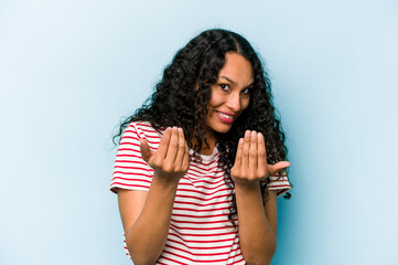 Young hispanic woman isolated on blue background pointing with finger at you as if inviting come closer.