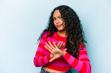 Young hispanic woman isolated on blue background doing a denial gesture