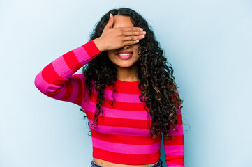 Young hispanic woman isolated on blue background covers eyes with hands, smiles broadly waiting for a surprise.