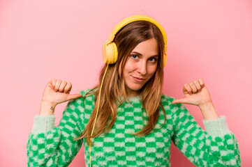 Young caucasian woman listening to music isolated on pink background feels proud and self confident, example to follow.