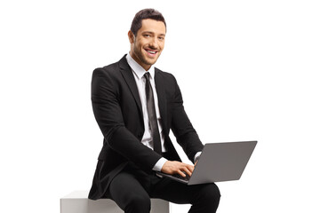 Businessman sitting and using a laptop computer, looking at the camera