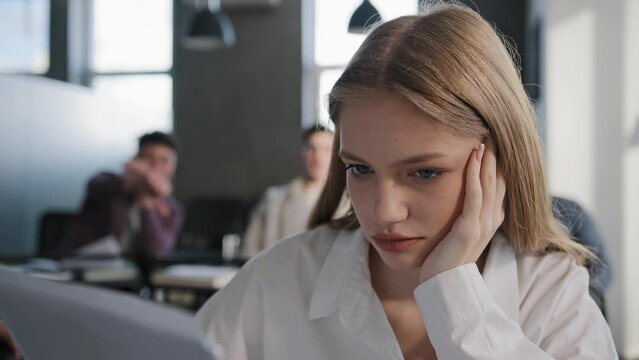 Close-up young caucasian upset girl student sitting alone in classroom at desk suffering from abuse ridicule bad attitude from classmates feels humiliated sad disappointed abandoned lonely offended