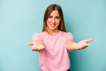 Young caucasian woman isolated on blue background showing a welcome expression.