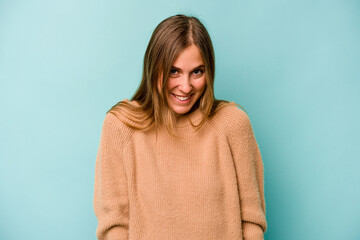 Fototapeta premium Young caucasian woman isolated on blue background laughs and closes eyes, feels relaxed and happy.