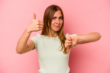 Young caucasian woman isolated on pink background showing thumbs up and thumbs down, difficult choose concept