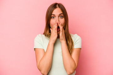 Young caucasian woman isolated on pink background shocked, covering mouth with hands, anxious to discover something new.