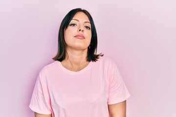 Young hispanic woman wearing casual pink t shirt relaxed with serious expression on face. simple and natural looking at the camera.