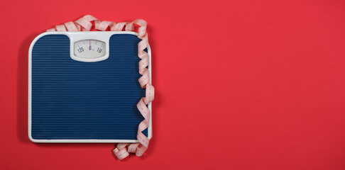 Floor blue scales and centimeter measuring tape on a red background, top view. The concept of weight loss and weight control