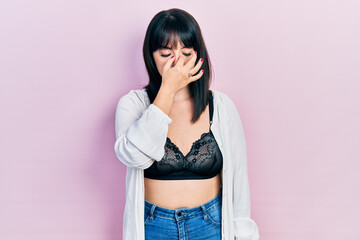 Young hispanic woman wearing lingerie tired rubbing nose and eyes feeling fatigue and headache. stress and frustration concept.