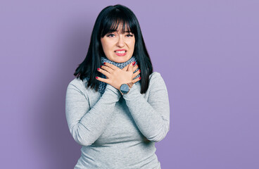 Young hispanic plus size woman wearing winter scarf shouting suffocate because painful strangle....