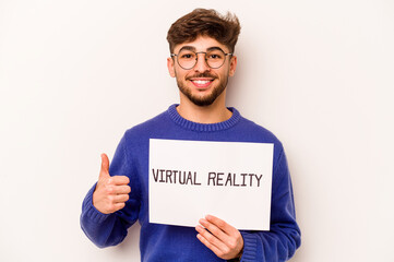 Young hispanic man holding a virtual reality placard isolated on white background smiling and raising thumb up