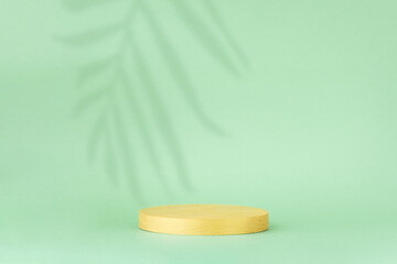 Minimal abstract background for the presentation of a cosmetic product. Golden scene on a green background with a shadow of tropical palm leaves. Premium podium, showcase, display case.