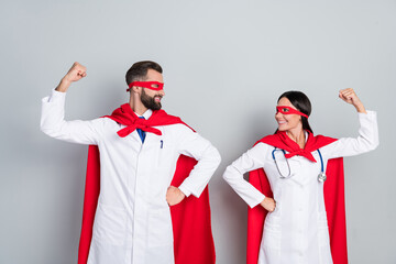 Portrait of two attractive cheerful docs super team rescue service show strong muscles isolated over grey color pastel background - obrazy, fototapety, plakaty