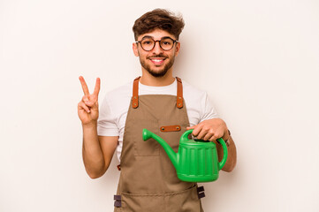 Young gardener hispanic man holding a watering can isolated on white background showing number two with fingers.