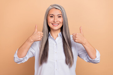Photo of mature lady show thumbs-up perfect feedback select ads isolated over beige color background