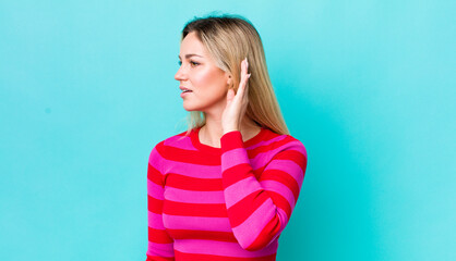 pretty blonde woman looking serious and curious, listening, trying to hear a secret conversation or...