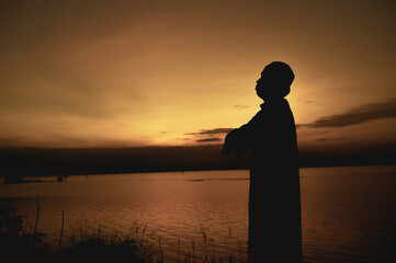 Silhouette Young asian muslim man praying on sunset,Ramadan festival concept