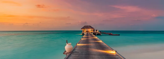 Fototapeten Amazing sunset island landscape at Maldives. Luxury resort water villas and jetty. Beautiful beach seascape with soft led lights colorful sky, background for vacation holiday. Paradise romance scenic © icemanphotos