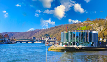 Namur, Belgium - March 9. 2022: View on confluence of river meuse and sambre with bridge, modern restaurant building, blue morning sky