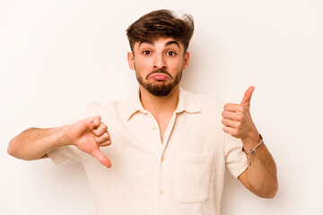 Young hispanic man isolated on white background showing thumbs up and thumbs down, difficult choose...