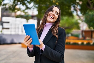 Young hispanic woman smiling confident using touchpad at park