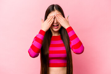 Young Chinese woman isolated on pink background covers eyes with hands, smiles broadly waiting for...