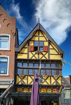 Sittard, Netherlands - March 25. 2022: Closeup of yellow half timbered ancient house facade against blue sky