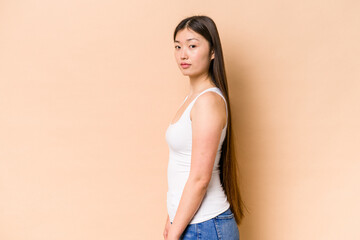 Young Chinese woman isolated on beige background