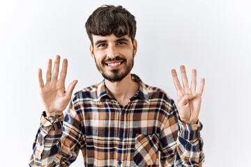 Naklejka premium Hispanic man with beard standing over isolated background showing and pointing up with fingers number nine while smiling confident and happy.