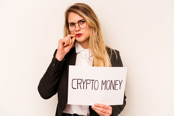 Young business caucasian woman holding a crypto money placard isolated on white background with fingers on lips keeping a secret.