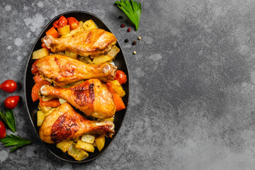 Spicy roast chicken with vegetables in cast iron skillet on dark background. Top view, copy space.