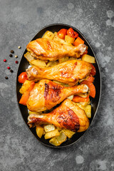 Balsamic roast chicken with vegetables in cast iron skillet on dark background. Top view, copy space.