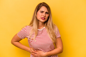 Young caucasian woman isolated on yellow background having a liver pain, stomach ache.