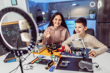Brother and sister make a robot and recording video in studio workshop.