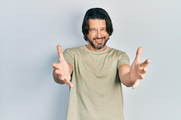 Middle age caucasian man wearing casual clothes looking at the camera smiling with open arms for hug. cheerful expression embracing happiness.