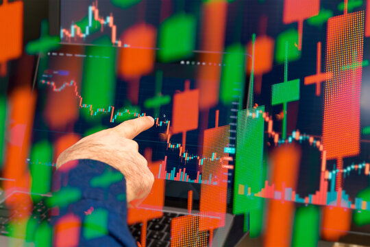 Global downtrend of the economy in world crisis. Man hand shows on the decreasing candle stick graph chart in the stock market, March 2022, San Francisco, USA