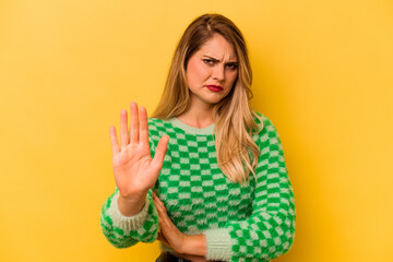 Young caucasian woman isolated on yellow background rejecting someone showing a gesture of disgust.