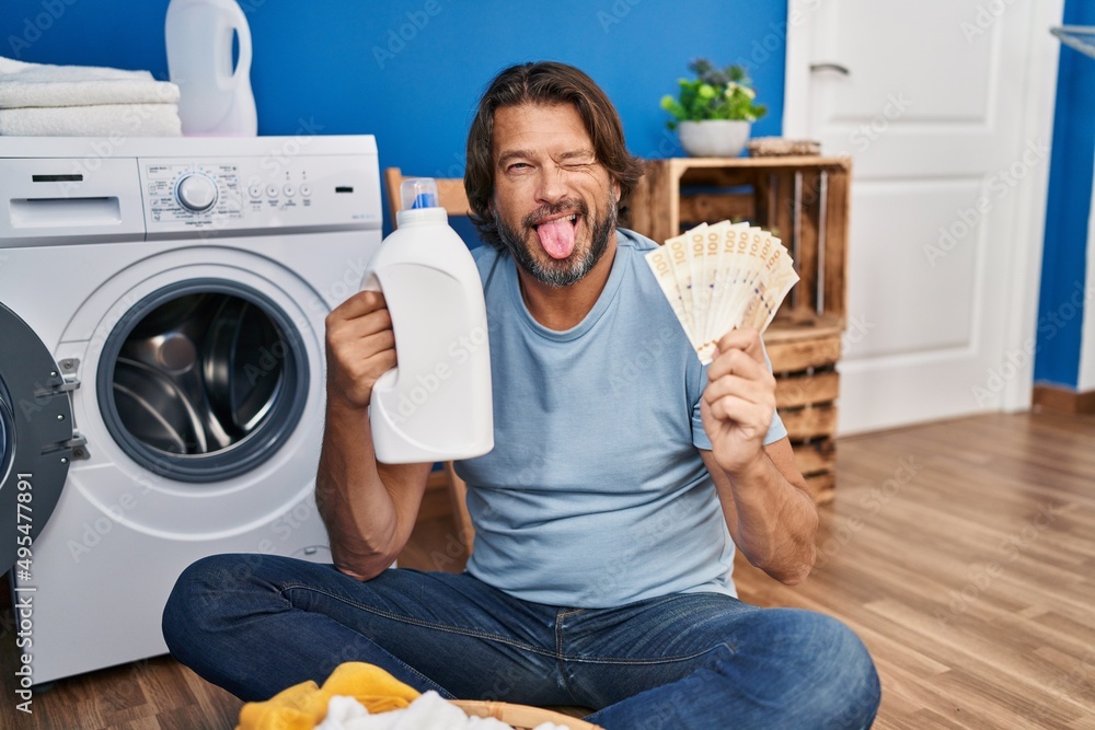 Sticker Handsome middle age man saving money of laundry detergent sticking tongue out happy with funny expression.