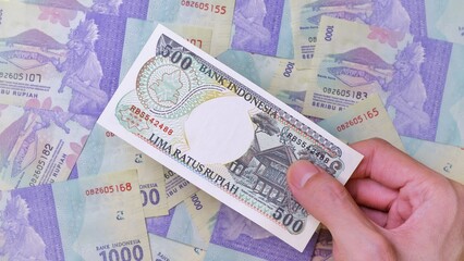 Indonesian Rupiah the official currency of Indonesia. Man's hand is making a payment. Business Saving Income Money Investment Economy and Finance Concept Uang 500 Rupiah. Five hundred Rupiah Indonesia