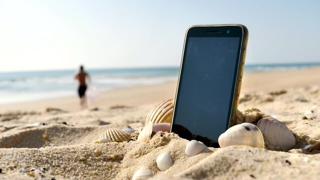 smartphone on the beach and man silhouette running to the sea- holiday, freedom or relax concept