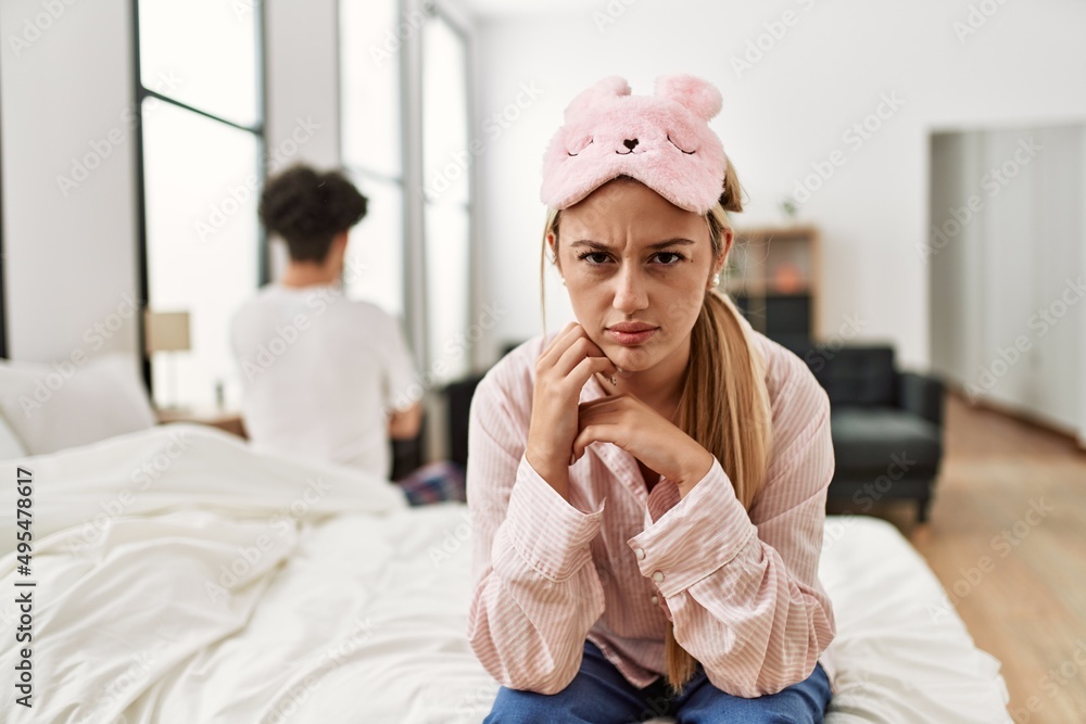 Poster Young beautiful couple in trouble. Sitting on the bed with hands on head.