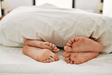 Couple feet under sheets on the bed at home.