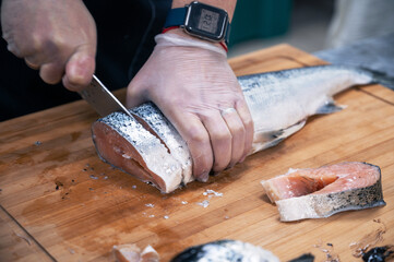 Chef preparing a salmon fish by gutting and filleting at the kitchen