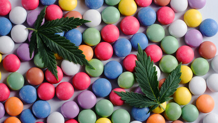 Marijuana sweets with CBD oil on white background. Cannabis leaves with colorful candy confetti close up. Top view, flat lay.
