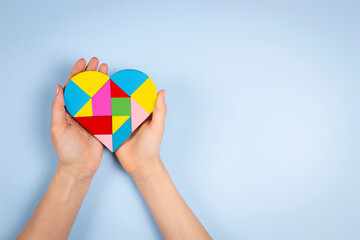World autism awareness day concept. Woman and child hands holding together colorful wooden puzzle...