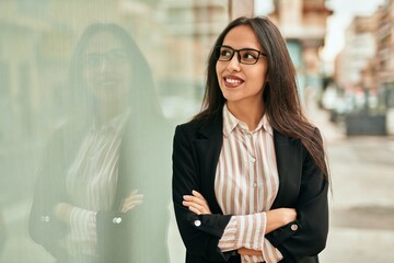 Young hispanic businesswoman smiling happy standing at the city.